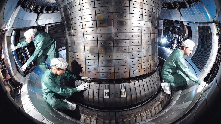 Fusionsanlage ASDEX Upgrade | Bildquelle: IPP Garching Das Bild zeigt drei Menschen, die Schutzbekleidung tragen und Arbeiten an der Versuchsanlage durchführen.