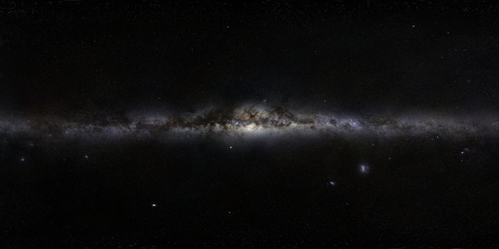 Ein 360-Grad-Panorama der Milchstraße Auf dunklen Untergrund erstreckt sich das helle Band der Milchstraße, teilweise durch Dunkelwolken verdeckt.