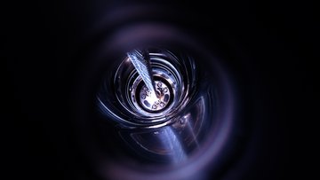 Eine zylinderförmige Anordnung aus Germaniumdetektoren wird durch einen Schacht in flüssiges Argon herabgelassen, Bildquelle: M. Heisel, GERDA collaboration; Lizenz: gemäß den Bedingungen der Quelle