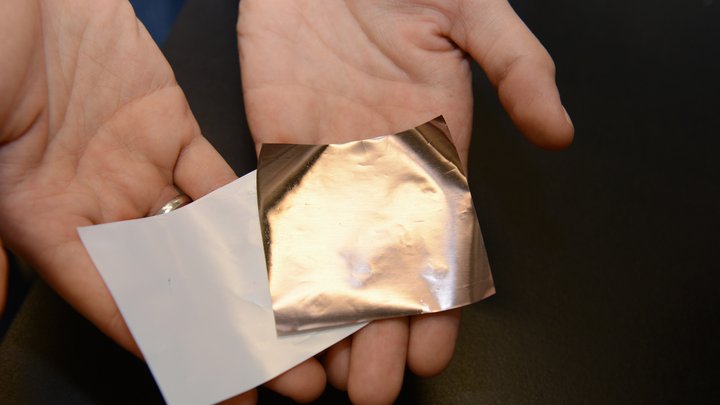 Eine kuoferfarbene und eine semitransparente Folie liegen in linker und rechter Hand