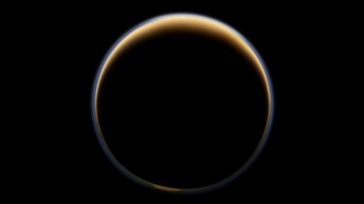 Gegenlicht erhellt die Atmosphäre, die Saturnmond Titan als leuchtender Ring umgibt.