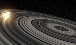 Planet mit ausgedehntem System aus Ringen, links scheint der Zentralstern durch die Ringe hindurch.