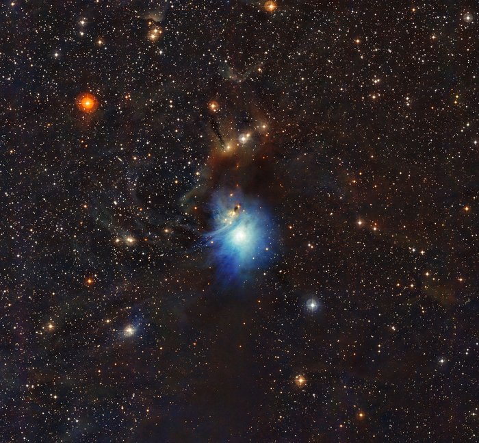 Ein Sternenhimmel in dessen Mitte ein heller ausgefranster Nebelfleck zu sehen ist.