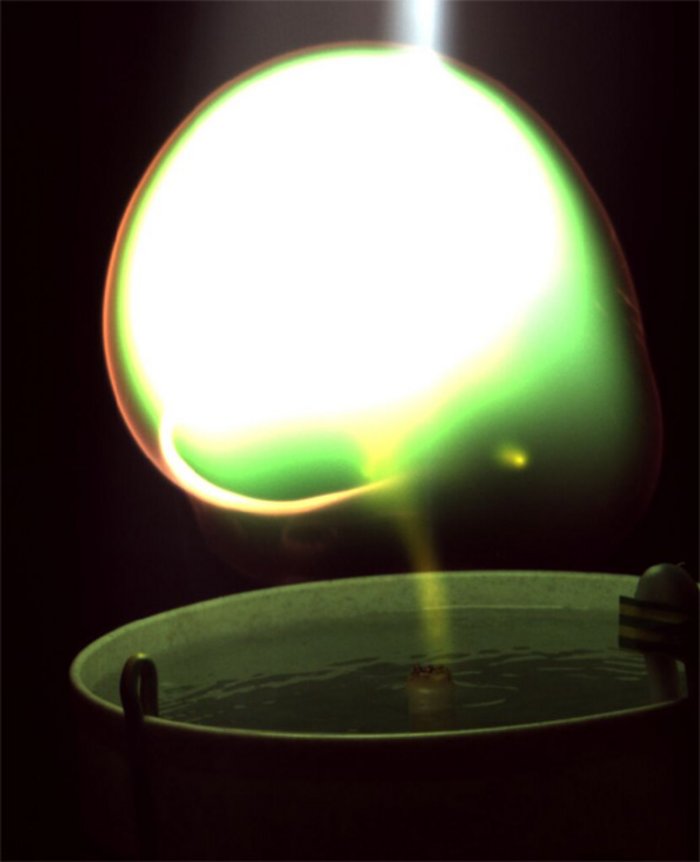 Künstlicher Kugelblitz Foto eines Wasserbads, über dem ein leuchtender Ball aus Plasma schwebt.