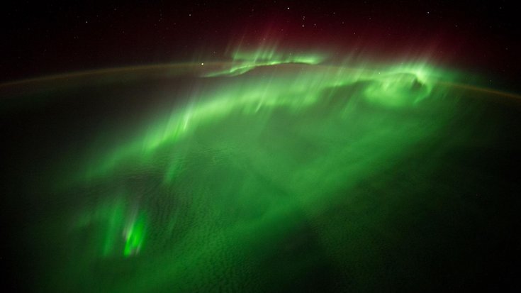 Blick aus dem Weltall auf die Erde. Es sind Polarlichter zu sehen.