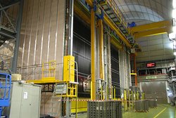 Bild eine großen Detektors mit Gerätschaften davor in einer Halle. 