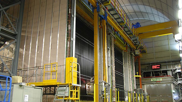 Bild eine großen Detektors mit Gerätschaften davor in einer Halle. 