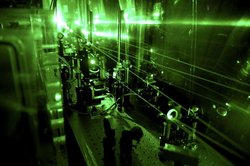 Messapparatur in einem dunklen Raum, von der grünes Laserlicht ausgeht.
