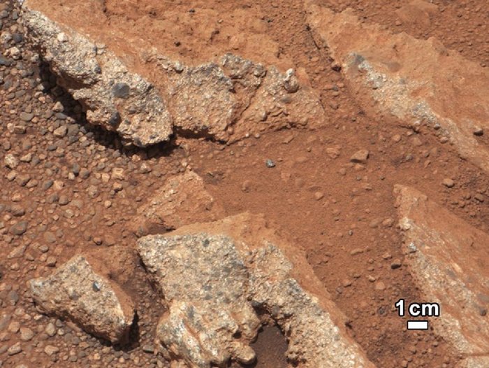 Aufgebrochene Steine und abgerundete Kiesel auf rotem Marsboden