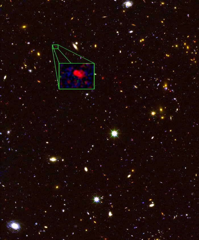 Etliche Galaxien sind als verschieden große und helle Flecken auf einem dunklen Hintergrund verteilt. Manche davon lassen Spiralarme erkennen. Die älteste spektroskopisch bestimmte Galaxie z8_GND_5296 ist in einem Kasten als roter Fleck vergrößert.