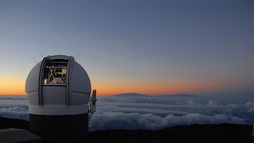 Ein Observatorium mit geöffneter Kuppel auf einem Berg über den Wolken. 