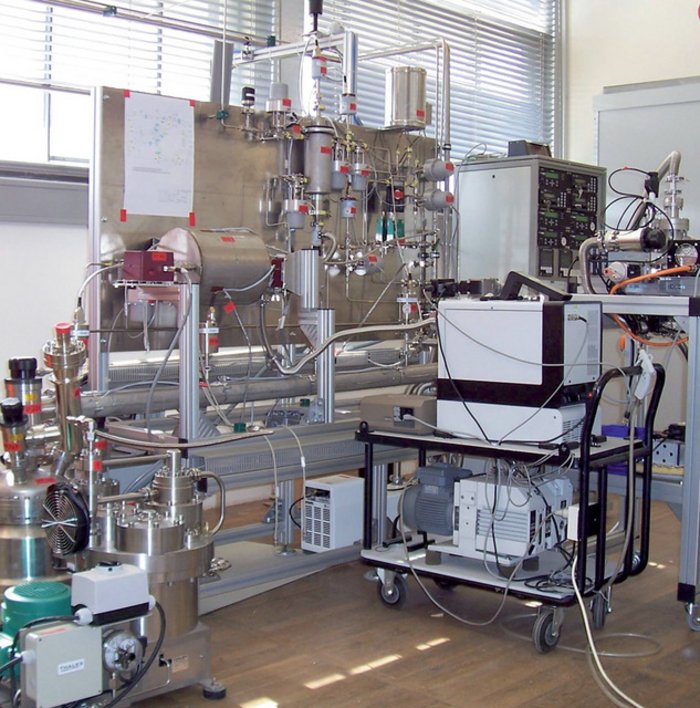 Das Testexperiment TILO Foto von einem Raum, in dem ein Versuchsaufbau mit zahlreichen Behältern steht, die mit Schläuchen und Kabeln verbunden sind.