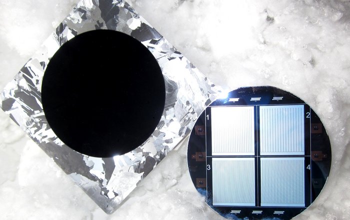 Solarzelle aus Schwarzem Silizium Links liegt die Vorderseite der Solarzelle aus schwarzem Silizium als ein dunkler Kreis inmitten eines Rechtecks, das silbrig glänzt. Daneben ist die Rückseite, ein Kreis mit vier Rechtecken, auf denen jeweils senkrechte Linien sind.