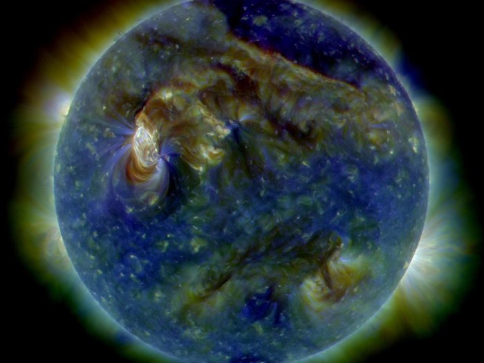 Sonnenaktivität Satellitenbild der Sonne, in Falschfarben dargestellt. Auf der ganzen formatfüllenden Sonne sind Verwirbelungen zu sehen, eine besonders große und helle links der Mitte. Sie hat etwa ein Zehntel Sonnendurchmesser, aus ihr ragen auch leichte Strahlen hervor. Von einem Strahlenkranz ist auch der Sonnenrand umsäumt.