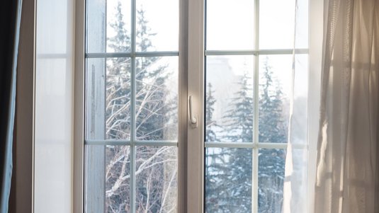 Das Foto zeigt den Blick aus einem Fenster in eine verschneite Landschaft.