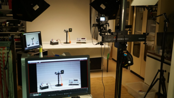 Verschiedene Laborgegenstände auf einem Tisch, darunter das Kamerabild dieser Szenerie auf einem Monitor