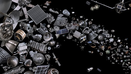 Collage aus zahlreichen Objekten aus der Raumfahrt vor schwarzem Hintergrund. Dargestellt sind ausgediente Satelliten, Raketenstufen, Treibstofftanks, Solarpaneele, Triebwerke und kleinere Metallteile und Schrauben.