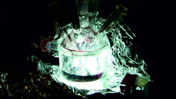 Das Bild zeigt eine experimentelle Vorrichtung, die von Aluminiumfolie umgeben und von innen beleuchtet ist.
