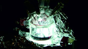 Das Bild zeigt eine experimentelle Vorrichtung, die von Aluminiumfolie umgeben und von innen beleuchtet ist.
