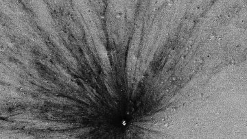 Kleiner heller Krater im Zentrum, von dem radial zahlreiche dunkle Strahlen ausgehen.