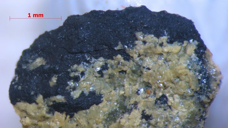 Natürliche MOFs, Bildquelle: T. Friščić et al./McGill University; Lizenz: gemäß den Bedingungen der Quelle Schwarzer Stein, der auf einer Seite von einem hellen Mineral überzogen ist