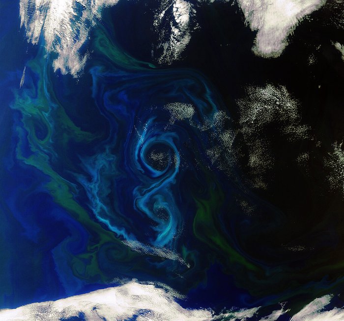 Phytoplankton im Südatlantik Das Meer von weit oben gesehen, nur wenige Wolken verdecken die Wasseroberfläche an den Rändern des Bilds. Im Zentrum sind deutlich ein großer Wirbel und ein kleineren Wirbel darunter zu sehen.
