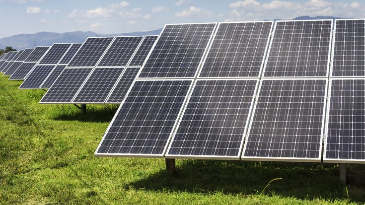 Solarmodule | Bildquelle: TodorovNikifor/Thinkstock Mehrere Solarmodule in einer Reihe hintereinander auf einer Wiese unter blauem Himmel