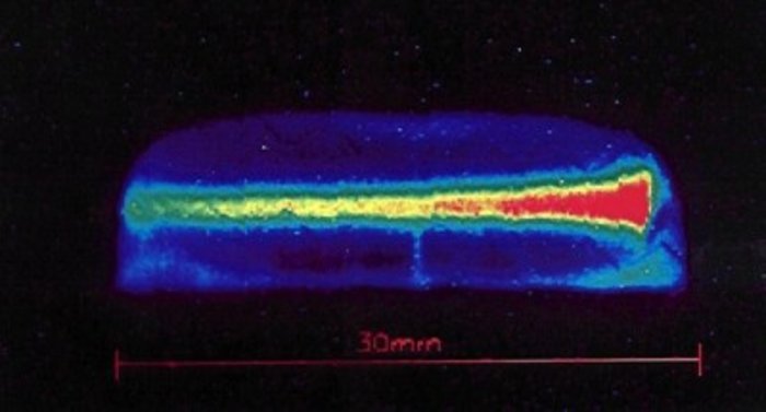 Foto eines Plasmas in einem gefrorenen Xenon-Kristall Blau-grün-gelb-roter Streifen auf schwarzem Hintergrund.