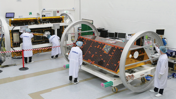 Test von GRACE Follow-On Foto eines Laborraums, in dem ein Satellit in eine Halterung eingespannt ist. Personen in Schutzkleidung untersuchen den Satelliten.