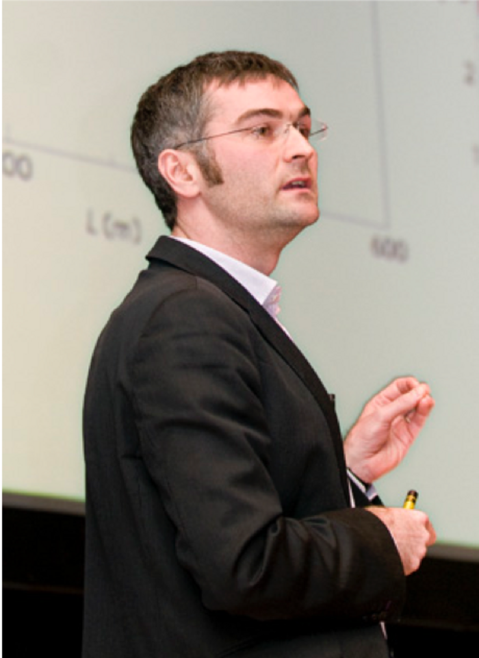 Das Bild zeigt den Forscher während er einen Vortrag hält.