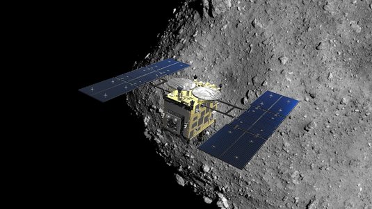 Eine satellitenartige Raumsonde vor einem großen Gesteinskörper mit felsiger Oberfläche im All