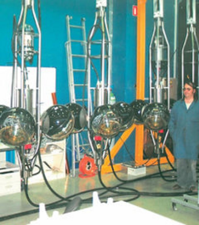 ANTARES-Stockwerke Foto in einer Arbeitshalle. Ein Mann betrachtet schwarze Kugeln an einer Aufhängung.