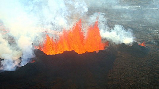 Luftaufnahme eines Vulkanausbruchs, bei dem glühende Lava in die Luft geschleudert wird.