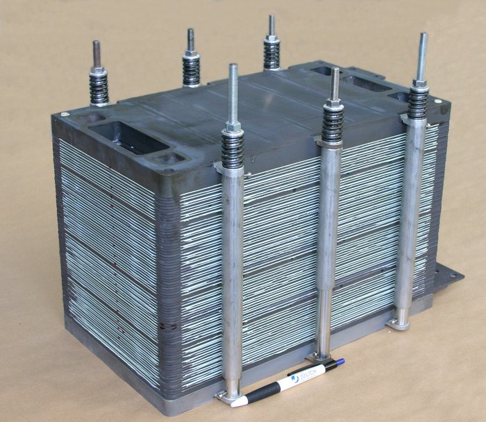 System aus planaren Brennstoffzellen Stapel aus grau-schwarzen, dünnen Platten, die übereinander in einem Metallgerüst liegen. Insgesamt bildet das System einen Block von etwa vierzig Zentimetern Länge.