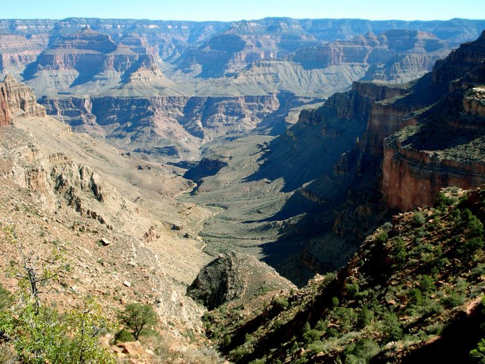 Grand Canyon Blick in eine der tiefen Schluchten, die umgebenden Hänge haben eine rötliche Farbe und sind nur spärlich bewachsen.