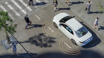 Straße mit Zebrastreifen, einigen Menschen und einem Auto.