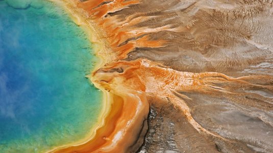 Auf dem Bild ist ein Ausschnitt der Grand Prismatic Spring, der größten Thermalquelle des Yellowstone-Nationalparks, zu sehen.