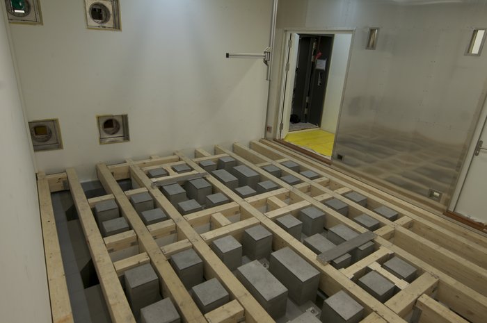 Betonstützen für empfindliche Aufbauten Quaderförmige Module, eingelassen im Boden eines fensterlosen Raums.