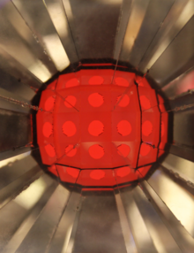 Farbige, kreisrunde Thermo-Solarzelle, strahlenförmig umgeben von kleinen Spiegeln.