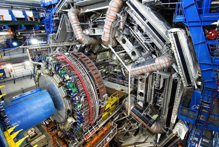 ATLAS-Kalorimeter Blick von schräg oben auf eine zylinderförmige Apparatur, die mit Hilfe von Schienen in ein Loch in der Mitte eines großen Teilchendetektors eingeschoben werden soll.