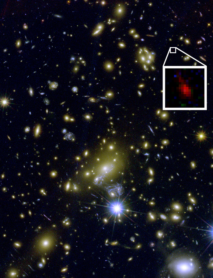 Blick in einen Galaxienhaufen. Ein Vergrößerungsfenster zeigt ein Sternsystem, das nur durch den Gravitationslinseneffekt sichtbar ist.