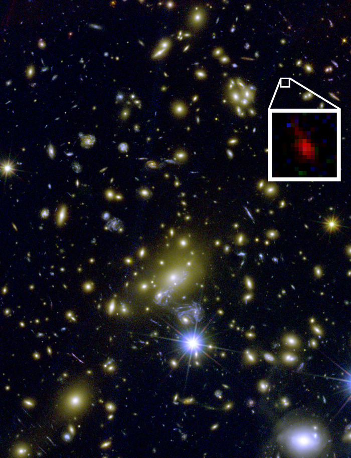 Der Galaxienhaufen MACS J1149+2223 wirkt als Gravitationslinse. Blick in einen Galaxienhaufen. Ein Vergrößerungsfenster zeigt ein Sternsystem, das nur durch den Gravitationslinseneffekt sichtbar ist.