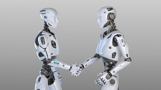 Zwei humanoide, weiß-silberne Roboter mit leuchtend blauen Augen stehen sich seitlich gegenüber und schütteln sich die Hand, vor neutralem hellgrauem Hintergrund. Sichtbare Gelenke und Kabel unterstreichen ihren technischen Aufbau.