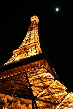 Eiffelturm, bei Nacht, illuminiert und mit Straßen- und Verkehrslichtern am Boden