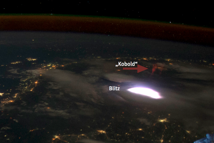 Blitz und Kobold über Myanmar Leuchterscheinung in der Erdatmosphäre, aufgenommen vom All aus bei Nacht. An den Seiten sind Solarpanele der Raumstation ISS zu sehen.