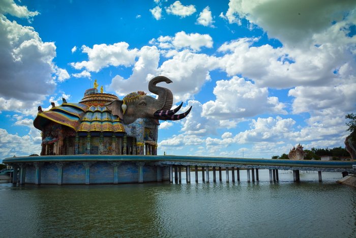 Tempel in Form eines Elefanten, reich verziert, auf einem Podest im See, über den eine Brücke zum Tempeleingang verläuft.