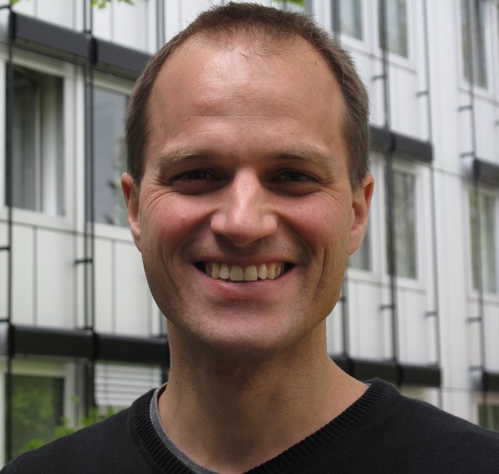 Christian Groß Das Bild zeigt den Forscher Christian Groß vor einem Fenster.