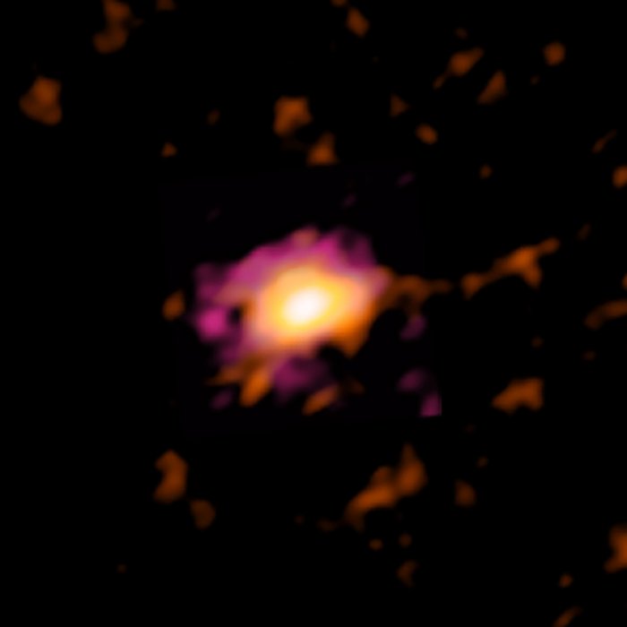 ALMA-Aufnahme Verschwommene Aufnahme einer scheibenförmigen Galaxie im All: Heller Fleck in dunkler Umgebung, der zum Rand hin erst orange und dann violett wird.