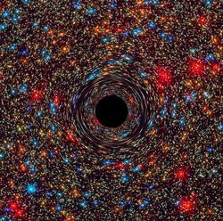 Im Zentrum einer Galaxie mit zahlreichen bunten Sternen und Himmelskörpern befindet sich ein kreisrundes Schwarzes Loch: Die Farbe stellt den Ereignishorizont dar, den keinerlei Materie oder Licht wieder überqueren kann, sobald sie ihn passiert haben. Zusätzlich erscheinen die Himmelskörper in der Nähe des Schwarzen Lochs verzerrt, da die große Schwerkraft des Schwarzen Lochs die Raumzeit krümmt. 