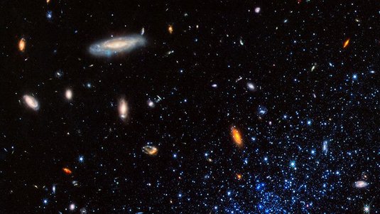 Leuchtende Sterne und Galaxien auf dunklem Hintergrund. Rechts unten häufen sich Sterne